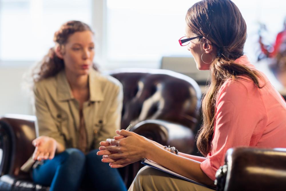 Dos mujeres hablando sentadas en sendos sillones